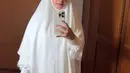 Gaya hijab yang dikenakan Annisa Pohan dalam foto ini adalah model mukena berwarna putih polos dengan desain sederhana namun elegan. Mukena ini memiliki potongan yang longgar dan nyaman, dengan aksen renda di bagian bawah yang menambah kesan anggun. (Liputan6.com/IG/@annisayudhoyono)