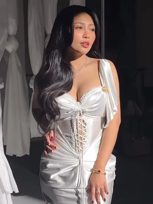 Pertama, Rachel tampil elegan bergaya vintage kenakan corset silk dress warna putih. Gaunnya menampilkan detail drapery dan sweetheart neckline yang menawan. [@rachelvennya].