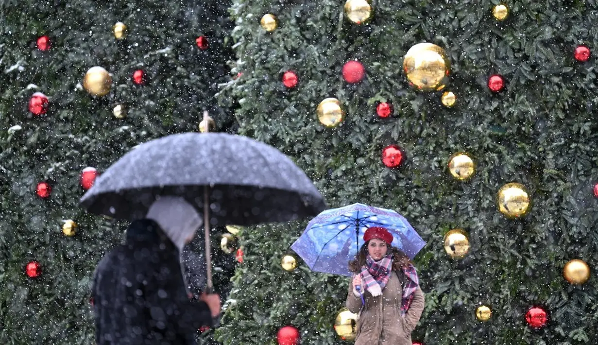 Orang-orang berjalan saat salju turun di Madrid, Spanyol, Jumat (8/1/2021). Badai Filomena mengakibatkan salju lebat turun di Madrid dan seluruh Spanyol. (GABRIEL BOUYS/AFP)