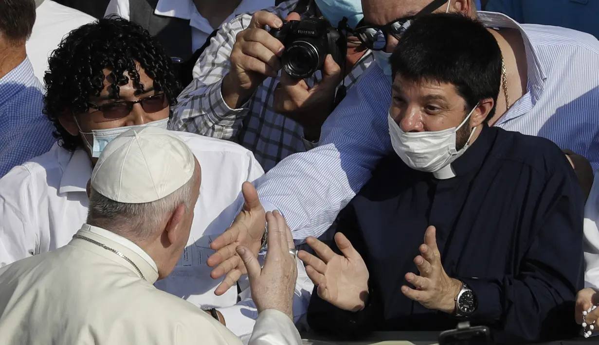 Paus Fransiskus menyapa umatnya yang memakai masker untuk mencegah penyebaran COVID-19 saat ia tiba di halaman St. Damaso pada kesempatan audiensi umum mingguannya di Vatikan, Rabu (16/9/2020). (AP Photo/Gregorio Borgia)