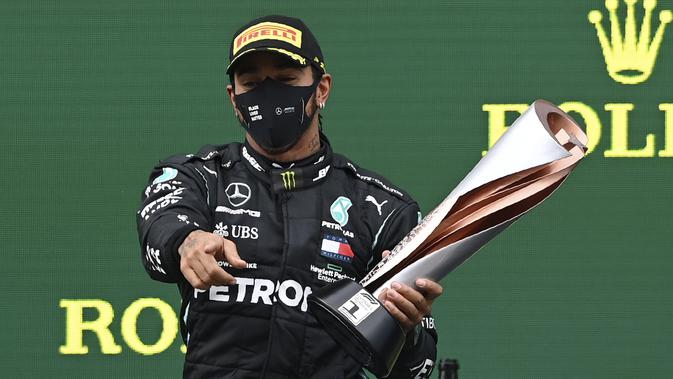 Pembalap Mercedes Lewis Hamilton berpose dengan piala saat merayakan kemenangan Grand Prix Formula Satu Turki di arena pacuan kuda Istanbul Park di Istanbul, Minggu (15/11/2020). (Ozan Kose/Pool via AP)