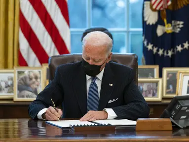 Presiden Amerika Serikat Joe Biden menandatangani Perintah Eksekutif yang membatalkan larangan bagi transgender untuk masuk militer AS pada era Donald Trump di Kantor Oval Gedung Putih, Washington, Senin (25/1/2021). (AP Photo/Evan Vucci)