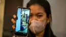 Seorang wanita memperlihatkan rekaman video suaminya sambil menunggu kabar terbaru tentang operasi pencarian dan penyelamatan kapal penumpang Mutiara Sentosa 2 di pelabuhan Tanjung Perak, Minggu (2/8/2026). (AFP/ Juni Kriswanto)