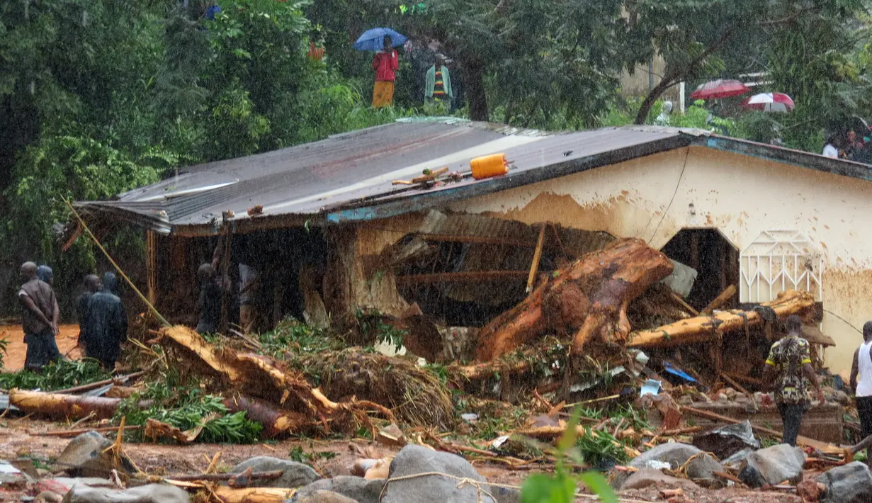 Petugas dibantu warga melakukan pencarian korban usai tanah longsor di Regent, Freetown, Sierra Leone, (14/8). Bencana ini terjadi saat penduduk tengah tidur sehingga banyak yang terjebak di dalam rumah. (AFP Photo/Saidu Bah)