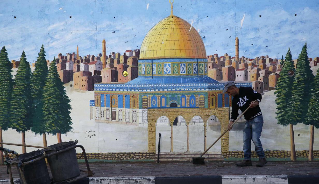 Pria Palestina menyapu jalan di Hebron di Tepi Barat yang diduduki Israel (7/12). Otoritas Palestina menyerukan demonstrasi di kota Ramallah di Tepi Barat menyusul keputusan Donald Trump mengakui Yerusalem sebagai ibu kota Israel. (AFP Photo/Hazem Bader)