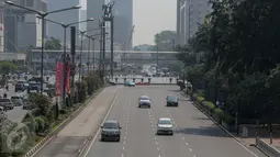 Sejumlah kendaraan bermotor melintasi kawasan Jalan Thamrin mengarah ke Sudirman, Jakarta, Kamis (18/6/2015). Pada hari pertama puasa Ramadan 1436 H, beberapa titik jalan terlihat lengang dan sepi dari aktivitas warga. (Liputan6.com/Faizal Fanani)