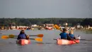 Para penonton mendayung perahu untuk menikmati konser musik Laivā di Danau Juglas, Riga, Latvia, 14 Agustus 2021. Hanya warga yang sudah divaksin COVID-19 yang diizinkan menonton konser dari darat. (Gints Ivuskans/AFP)