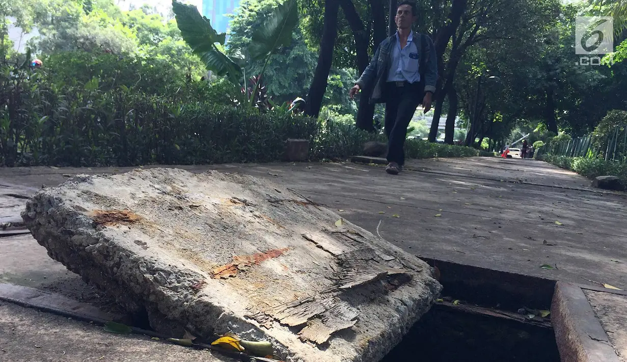 Pejalan kaki melintasi trotoar yang rusak dan berlubang di Jalan Kyai Tapa, Jakarta, Kamis (24/1). Banyaknya lubang akibat kerusakan penutup saluran air tersebut membahayakan pejalan kaki. (Liputan6.com/Immanuel Antonius)