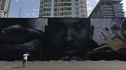 Nate Edwards mengambil gambar mural yang menggambarkan Kobe Bryant dan putrinya, Gianna, di Los Angeles, Rabu, 24 Agustus 2022. Mural, yang dilukis oleh seniman jalanan Portugis Odeith dan seniman dan ilustrator kontemporer Amerika Nikkolas Smith tersebut untuk merayakan Kobe Bryant Day. (AP Photo/Jae C. Hong)