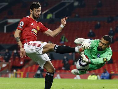 Penyerang Manchester United, Bruno Fernandes, berebut bola dengan kiper Brighton and Hove Albion, Robert Sanchez, pada laga Liga Inggris di Stadion Old Trafford, Minggu (4/4/2021). MU menang dengan skor 2-1. (Phil Noble/Pool via AP)