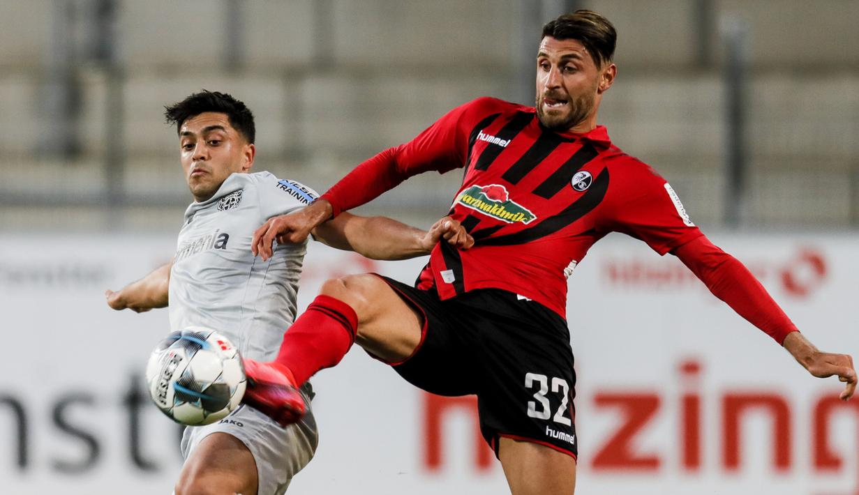 Gelandang Bayer Leverkusen, Nadiem Amiri, berebut bola dengan pemain Freigurg pada laga pekan ke-29 Bundesliga 2019/20 di Schwarzwald-Stadion, Sabtu (30/5/2020) dini hari WIB. Leverkusen menang 1-0 atas Freiburg. (AFP/Ronald Wittek/pool)
