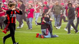 Dua orang suporter Bayer Leverkusen berpelukan saat merayakan keberhasilan timnya menjuarai Liga Jerman 2023/2024 setelah mengalahkan Werder Bremen di BayArena, Leverkusen, Jerman, Senin (15/04/2024) WIB. (AP Photo/Martin Meissner)