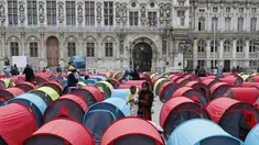 Seorang imigran perempuan menggendong banyinya di kamp darurat yang didirikan di luar balai kota Paris, Jumat (25/6/2021). Lebih dari 300 migran mendirikan sekitar 200 tenda di luar balai kota untuk menarik perhatian terhadap kondisi mereka dan menuntut akomodasi. (AP Photo/Lewis Joly)