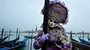 Peserta mengenakan kostum dan topeng berpose untuk difoto saat berpartisipasi dalam Karnaval Venesia di Italia (27/1). Ciri khas dari karnaval ini adalah Topeng Venesia yang terbuat dari kulit atau akrilik. (AFP Photo/Filippo Monteforte)