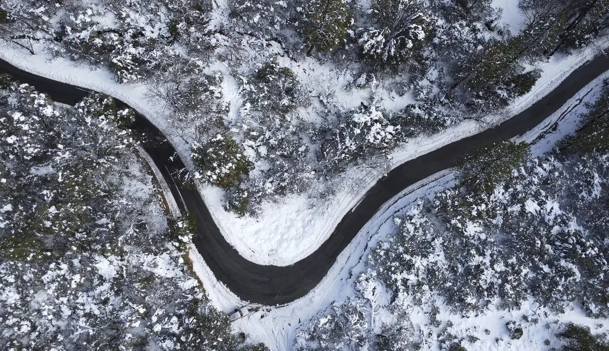 Salju membatasi setiap sisi Coyote Street saat jalan berkelok-kelok di sepanjang sisi Sugarloaf Mountain di Nevada City, California, Selasa (28/12/2021). (Elias Funez/The Union via AP)