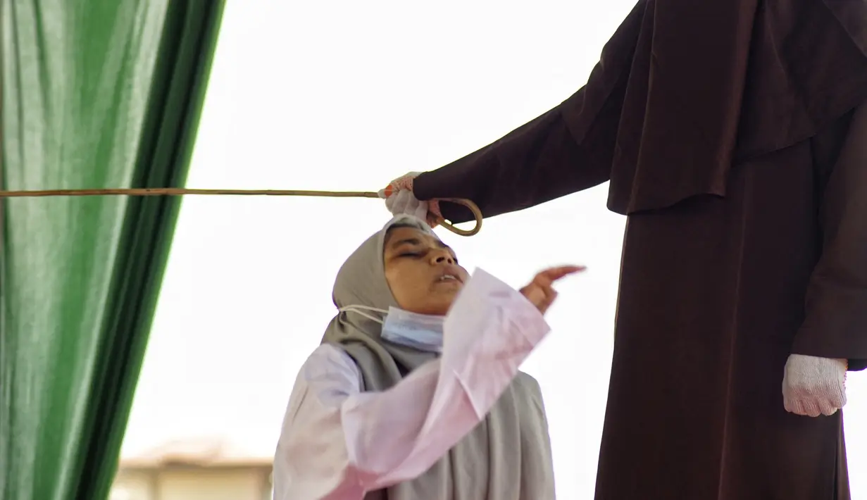 Seorang wanita bereaksi saat dia dicambuk di depan umum oleh anggota polisi Syariah di Lhokseumawe, Aceh, Senin (28/6/2021). Wanita yang didakwa telah melakukan hubungan seks pranikah itu dihukum dengan 100 cambukan. (Azwar Ipank/AFP)