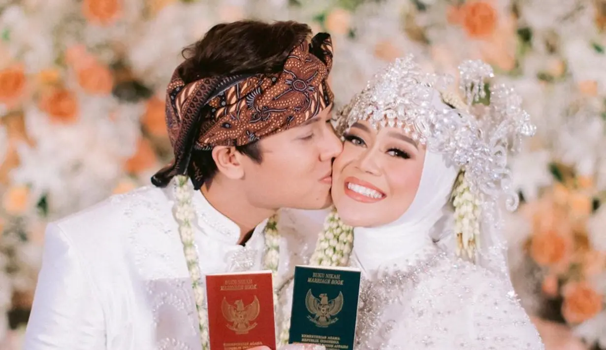 Foto pernikahan rasanya kurang sah tanpa pose pamer buku nikah. Ini pula yang dilakukan Rizky Billar disertai status teks ringkas, “Akhirnya bisa pamer buku nikah.” Saat artikel ini disusun, foto ini disukai lebih dari 1,8 juta orang dan kebanjiran 16 ribuan komentar. Kala itu pernikahan Rizky Billar dan Lesti Kejora disiarkan stasiun televisi swasta. (Foto: Dok. Instagram @rizkybillar)