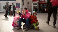 Anak-anak duduk di barang bawaannya di luar Stasiun Kereta Api Beijing, China (9/2). Sambut perayaan Imlek 2018, Jutaan warga China mulai memenuhi stasiun, bandara dan jalan yang diperkirakan akan dimulai akhir pekan ini. (AP Photo / Mark Schiefelbein)