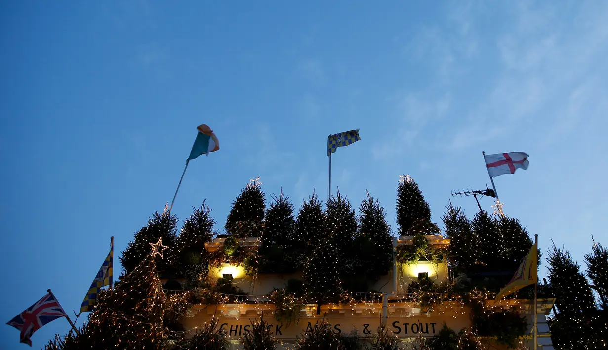 Pohon natal dan lampu warna-warni menutupi bangunan bar Churchill Arms di London, Inggris, 20 Desember 2016. Dalam rangka menyambut Natal, lebih dari 80 pohon natal dan hampir 22.000 lampu berkelap-kelip tampak menghiasi bar tersebut. (REUTERS/Neil Hall)