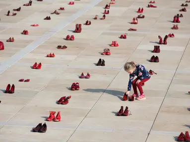Seorang anak di antara instalasi ratusan sepatu merah untuk memprotes kekerasan terhadap perempuan di Habima Square, Tel Aviv, Selasa (4/12). Sepanjang tahun ini, 24 perempuan Israel tewas akibat tindakan kekerasan dalam rumah tangga. (AP/Oded Balilty)