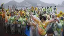 Sejumlah relawan bersorak sambil mengenakan jas hujan usai dibatalkannya kompetisi cabang dayung Olimpiade 2016 akibat cuaca buruk di stadion Lagoa, Rio de Janeiro, 10 Agustus 2016. (AFP PHOTO/Damien Meyer)