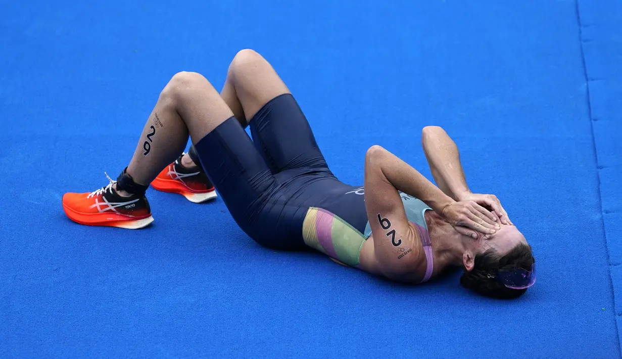 Atlet Bermuda, Flora Duffy berbelebrasi setelah melewati garis finis untuk meraih medali emas dalam triathlon nomor individu putri Olimpiade Tokyo 2020 di Odaiba Marine Park, Selasa (27/7/2021). Flora Duffy menjadi penyumbang medali emas untuk negara berpenduduk 60 ribu orang itu. (AP/David Goldman)