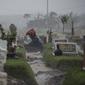 Seorang warga berdoa di tengah hujan deras di makam keluarganya di lahan khusus korban Covid-19 di TPU Keputih, Surabaya, Jawa Timur, Kamis (7/1/2020). Total sembuh 17.006 dan 1.256 meninggal dunia. (AFP/Juni Kriswanto)