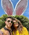 Pasangan Nick Jonas dan Priyanka Chopra merayakan Paskah dengan outfit bernuansa kuning. Priyanka memilih kemeja kuning polos, sedangkan Nick Jonas mengenakan sweater rajut berkerah dengan motif abstrak. Keduanya berpose selfie di depan dekorasi taman berbentuk telinga kelinci yang gemas. Foto: Instagram.