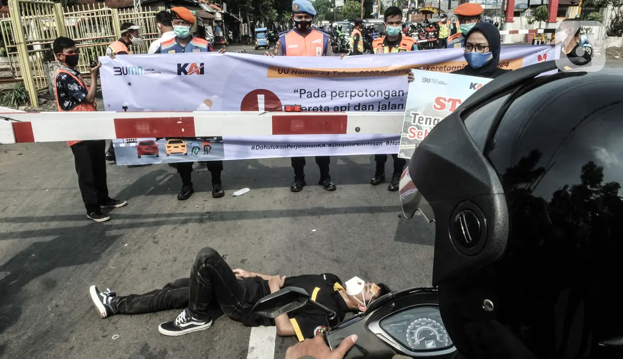 Petugas PT KAI saat sosialisasi keselamatan di perlintasan kereta api sebidang, Kemayoran, Jakarta, Rabu (14/10/2020). PT KAI Daop 1 menggelar sosialisasi dan aksi teatrikal dalam rangka menekan angka kecelakaan yang kerap terjadi di perlintasan sebidang. (merdeka.com/Iqbal Nugroho)