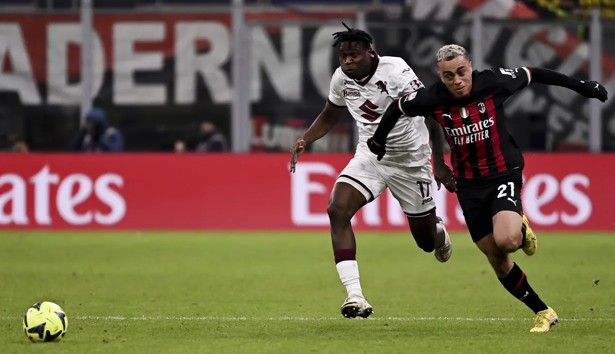 Bek AC Milan, Sergino Dest berlari berebut bola dengan pemain Torino, Stephane Singo pada pertandingan babak 16 besar Coppa Italia di Stadion San Siro di Milan, Italia, Kamis (12/1/2023). Torino menang tipis atas AC Milan dengan skor 1-0 berkat gol Michel Adopo di perpanjangan waktu. (Marco Alpozzi/LaPresse via AP)