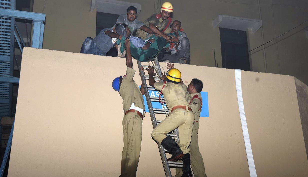 Salah satu korban berhasil dievakuasi oleh petugas pemadam saat kebakaran melanda rumah sakit SUM Bhubaneshwar di Odisha, India Timur, Senin (17/10). Sebagian besar korban dilaporkan meninggal karena kehabisan napas akibat menghirup asap. (AFP)