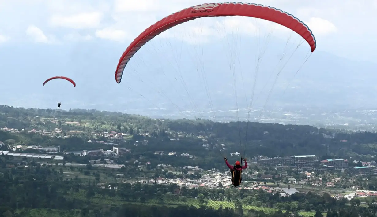 Seorang paraglider lepas landas dari lereng bukit di Puncak, Bogor, Jawa Barat, Kamis (2/12/2021). Destinasi wisata alam Bukit Paralayang Puncak Bogor sangat cocok untuk dikunjungi pada liburan akhir pekan bersama keluarga, sahabat maupun pasangan tercinta. (Goh Chai Hin/AFP)