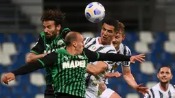 Striker Juventus, Cristiano Ronaldo (kanan) berduel udara dengan bek Sassuolo, Vlad Chiriches dalam laga lanjutan Liga Italia 2020/2021 pekan ke-36 di Mapei-Citta del Tricolore Stadium, Rabu (12/5/2021). Juventus menang 3-1 atas Sassuolo. (AFP/Marco Bertorello)