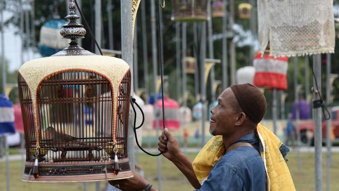 Seorang peserta menyiapkan burung peliharaannya saat mengikuti kontes burung berkicau di Provinsi Narathiwat di Thailand selatan (22/9/2019). Lebih dari 1.800 burung dari Thailand, Malaysia, dan Singapura mengambil bagian dalam kontes tahunan. (AFP Photo/Madaree Tohlala)