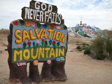 Sebuah tanda yang menandai pintu masuk ke Salvation Mountain, sebuah lereng bukti di Niland, California, Amerika Serikat. Dibuat oleh penduduk lokal bernama Leonard Knight, Salvation diisi dengan banyak seni lukis berupa mural dengan kutipan Kristen dan ayat-ayat Alkitab. (Robyn Beck/AFP)