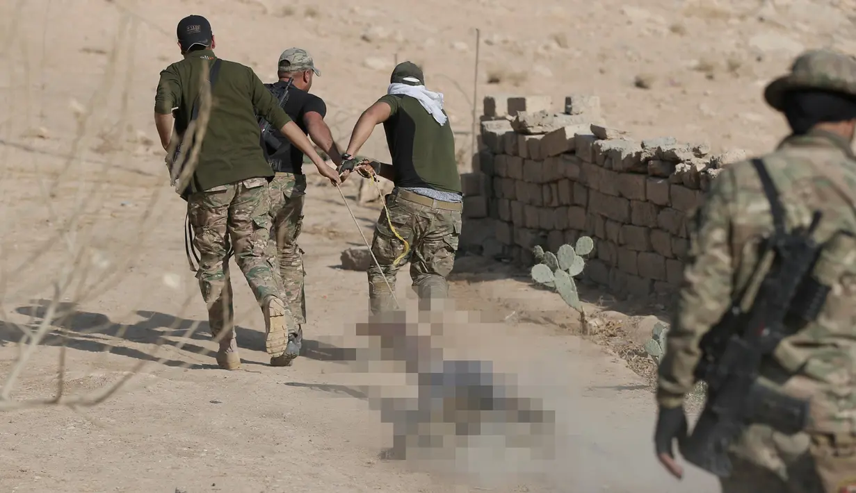 Para tentara Irak menyeret jenazah militan ISIS  dengan tali sebelum dimakamkan di dekat Karmah, selatan Mosul, Irak (11/11). Jenazah kelompok ISIS ditemukan tewas setelah terlibat kontak senjata dengan pasukan koalisi Irak. (REUTERS/Goran Tomasevic)