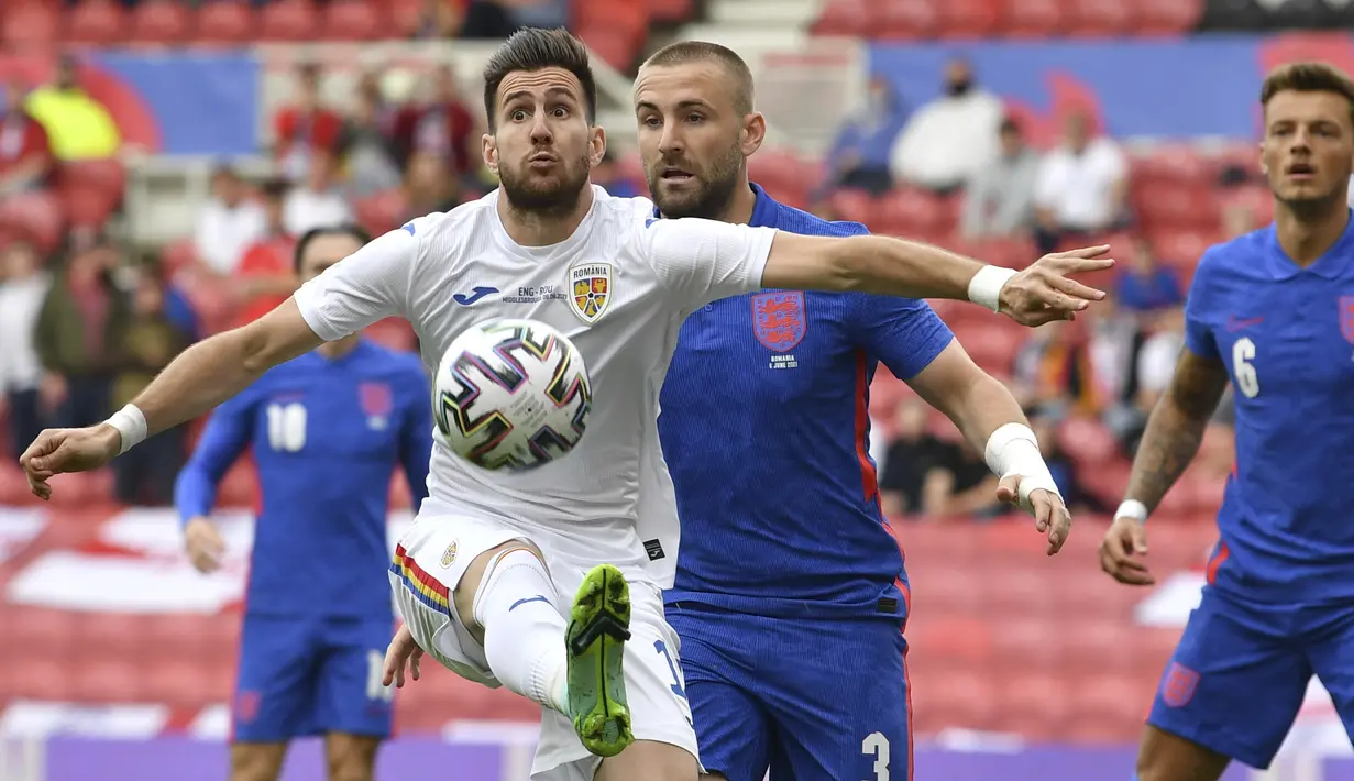 Gelandang timnas Rumania, Adrian Paun menendang bola di sebelah bek Timnas Inggris, Luke Shaw pada laga pemanasan jelang Piala Eropa 2020 di Riverside Stadium, Minggu (6/6/2021). Bertanding menghadapi Rumania, Inggris menang tipis 1-0. (Paul Ellis, Pool via AP)