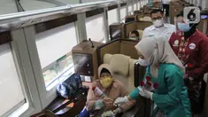 Petugas PT KAI Daop 1 Jakarta membagikan bunga kepada penumpang di Stasiun Gambir, Rabu (21/4/2021). PT KAI DAOP 1 memperingati Hari Kartini menginspirasi para penumpang agar semangat berjuang melawan pandemi COVID-19 dengan selalu menerapkan protokol kesehatan. (Liputan6.com/Herman Zakharia)