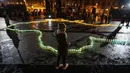 Seorang gadis berdiri di depan lilin yang menyala membentuk peta Ukraina di depan monumen Taras Shevchenko, di Lviv, Ukraina barat, Selasa malam (5/4/2022). Orang-orang Ukraina berkumpul untuk momen menghormati nyawa yang hilang dalam perang. (AP Photo/Nariman El- Mofty)