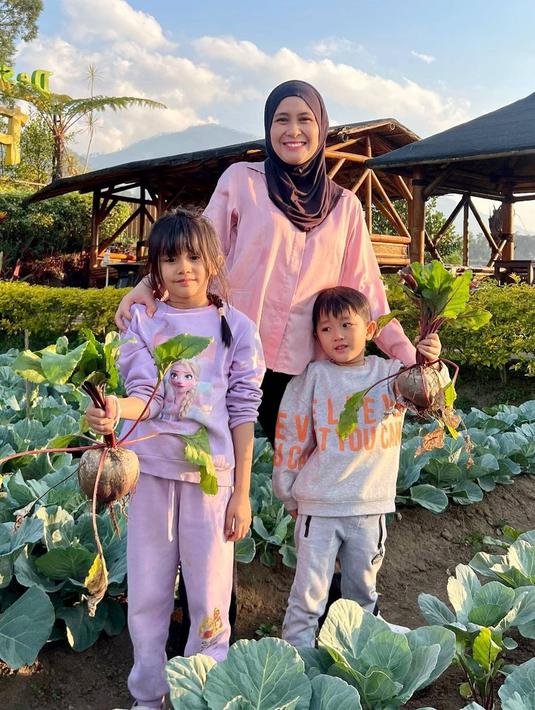 Tidak hanya menikmati serunya jalan-jalan dengan menikmati pemandangan alam. Ryana Dea juga mengajak kedua buah hatinya mengunjungi kebun untuk memetik buah bit dan tomat secara langsung. Wisata seperti ini tentu bikin anak-anak antusias, apalagi biasanya tinggal di kota besar. (Liputan6.com/IG/@ryana_dea)