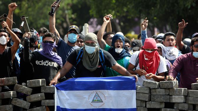 Para pengunjuk rasa bertopeng memblokade jalan di dekat Universitas Politecnica de Nicaragua (UPOLI), Managua, Nikaragua, Sabtu (21/4). Sepuluh orang tewas dari pihak demonstran dan petugas kepolisian. (AP Photo/Alfredo Zuniga)