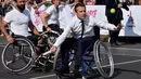 Presiden Prancis Emmanuel Macron didampingi petenis tenis Prancis, Michael Jeremias (kiri) bermain tenis diatas kursi roda di Paris, Prancis (24/6). (AFP Photo/Alain Jocard)