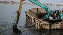 Kendaraan eskavator dan tongkang Dinas Tata Air DKI Jakarta mengeruk lumpur dan sampah dari Waduk Pluit, Jakarta, Selasa (11/12). Pengerukan ini dilakukan untuk menambah kedalaman waduk. (Liputan6.com/Faizal Fanani)