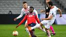 Gelandang Lille, Jonathan Bamba, berusaha melewati pemain AC Milan pada laga lanjutan laga lanjutan Liga Europa di Stade Pierre Mauroy, Jumat (27/11/2020) dini hari WIB. AC Milan bermain imbang 1-1 menghadapi Lille. (AFP/Dennis Charlet/pool)