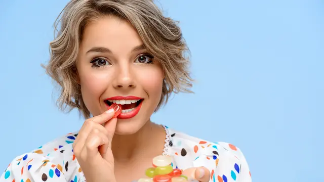 Seorang perempuan sedang menggigit sebuah permen (Foto Dok: Freepik/cookie_studio)