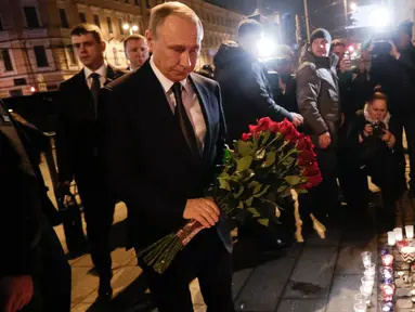 Presiden Rusia, Vladimir Putin membawa karangan bunga di dekat lokasi ledakan bom di stasiun kereta bawah tanah di St. Petersburg, Senin (3/4). Putin memberi penghormatan kepada para korban ledakan yang terjadi di lokasi itu. (AP Photo/Dmitri Lovetsky)