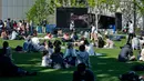 Orang-orang mendengarkan pertunjukan selama konser "The Pianist Special", dimainkan di dalam ruangan dan secara bersamaan disiarkan ke area terbuka sebuah pusat perbelanjaan di Tachikawa, Tokyo (11/4/2021). (AFP Photo/ Philip Fong)