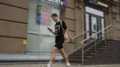 Seorang pria berjalan melewati kantor penukaran mata uang di Moskow, Rusia, Senin, 14 Agustus 2023.  (AP Photo/Alexander Zemlianichenko)
