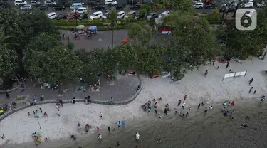 Pemandangan udara warga berlibur di Pantai Ancol, Pademangan, Jakarta Utara, Rabu (1/6/2022). Libur Nasional Hari Lahir Pancasila, dimanfaatkan warga mengajak sanak saudara tamasya di Pantai Ancol. (Liputan6.com/Herman Zakharia)