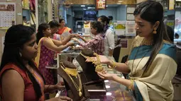 Pekerja melayani seorang perempuan yang berbelanja perhiasan emas pada hari Akshay Tritiya yang dianggap menguntungkan untuk membeli emas di Mumbai, India, Selasa (3/5/2022). Membeli emas adalah kegiatan yang populer di Akshaya Tritiya, karena ini adalah simbol utama kekayaan dan kemakmuran. (AP Photo/Rajanish kakade)&nbsp;